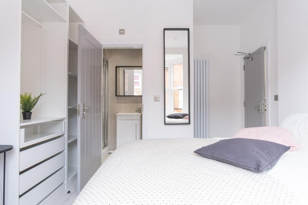 A bright and tidy bedroom featuring a neatly ma...