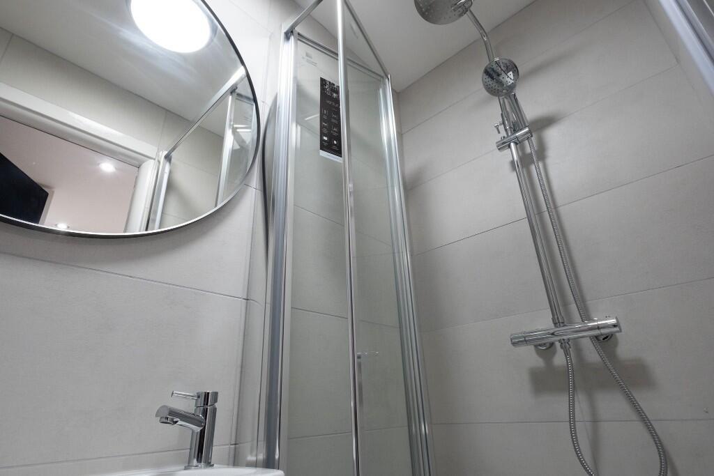 A modern, clean bathroom featuring a shower uni...