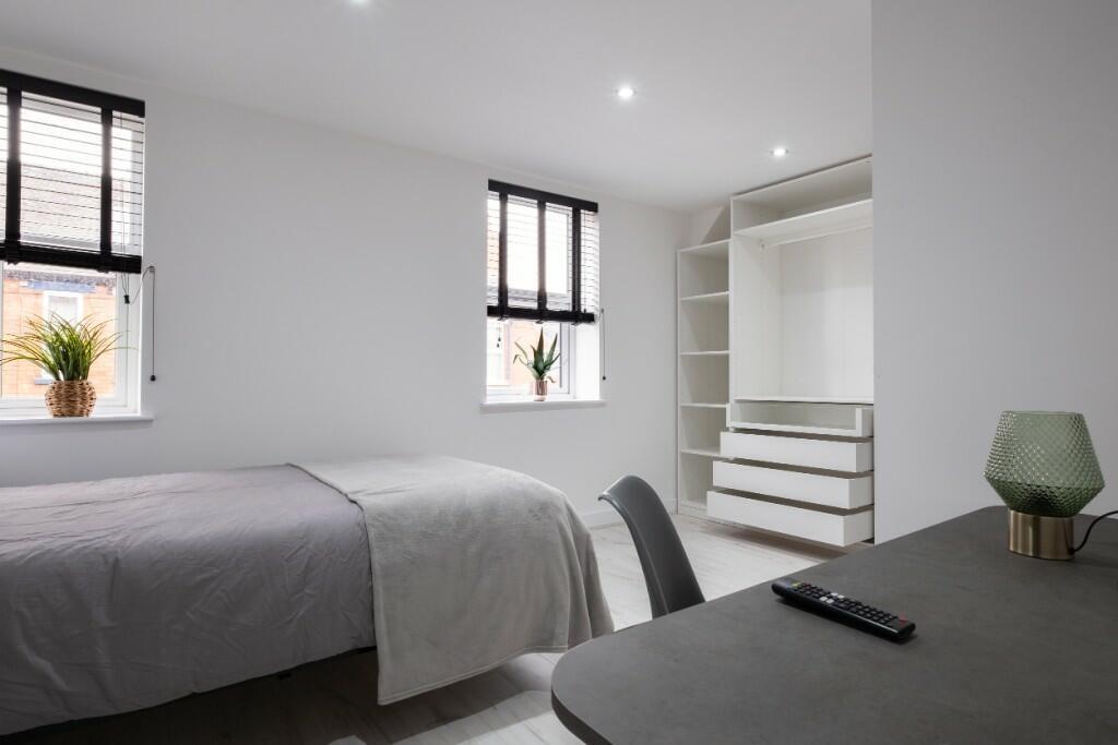 A bright and clean bedroom with two windows pro...