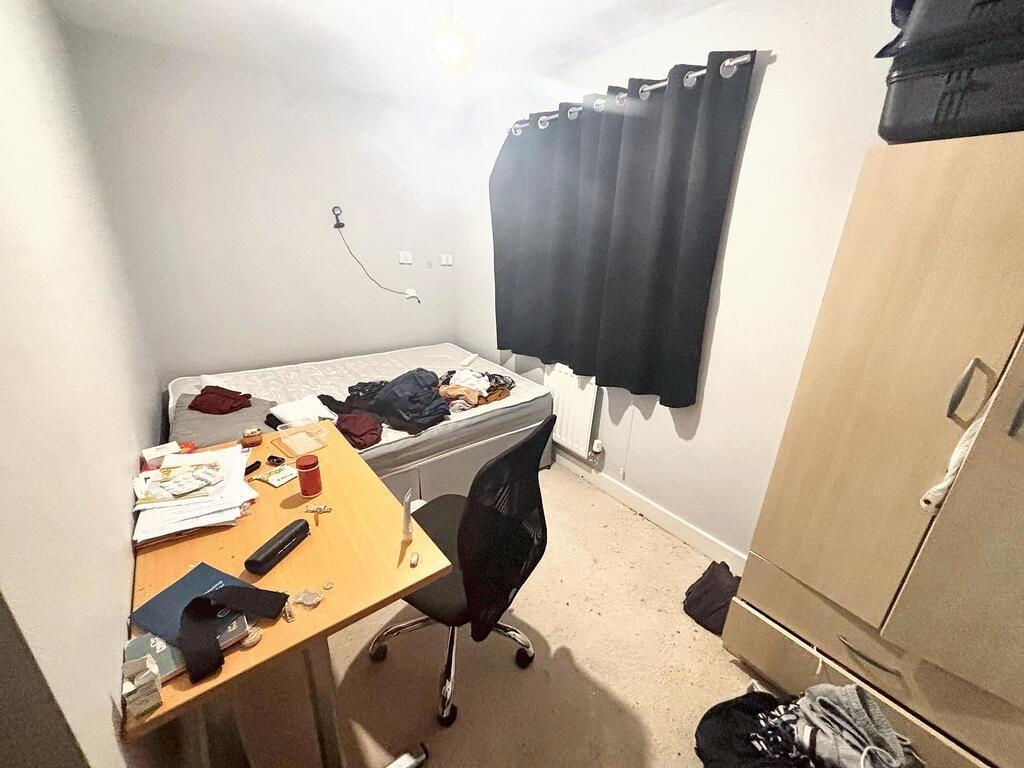 A modest bedroom featuring a single bed, a smal...