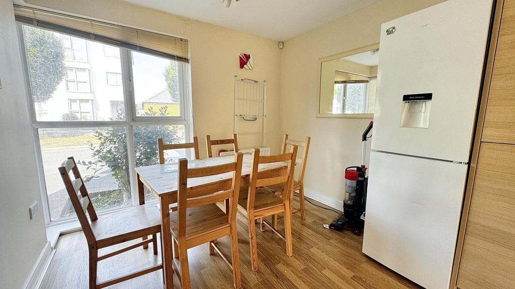 Bright dining area with a wooden table and chai...