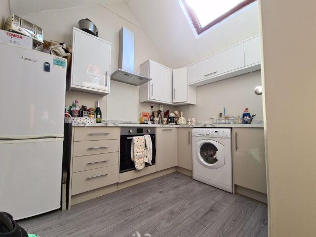 A modern, well-lit kitchen area with white cabi...