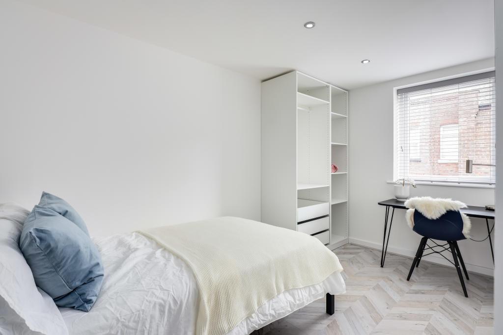 A bright, neatly maintained bedroom with a comf...