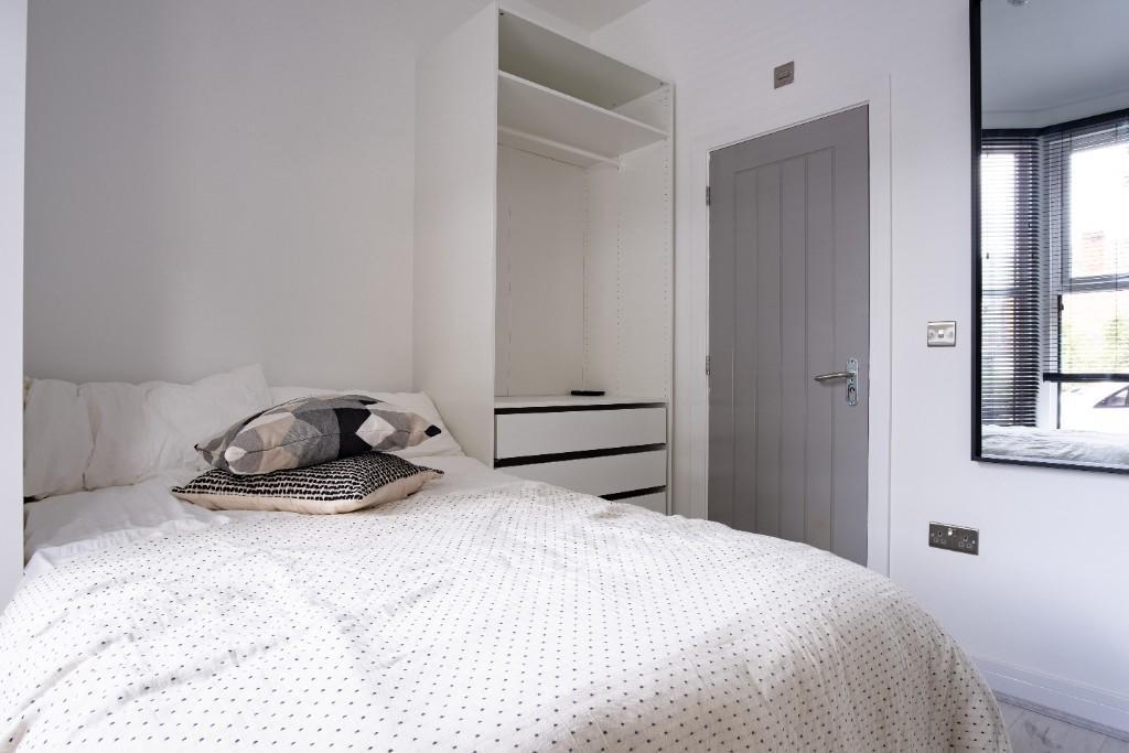 A bright and cozy single bedroom featuring a co...
