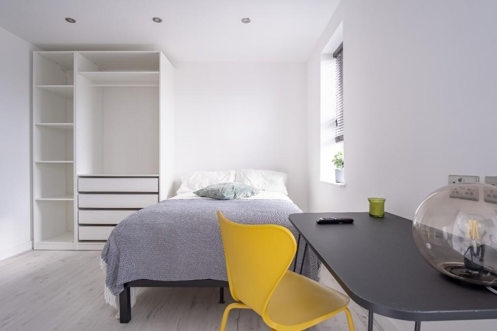A bright, modern bedroom featuring a neatly mad...