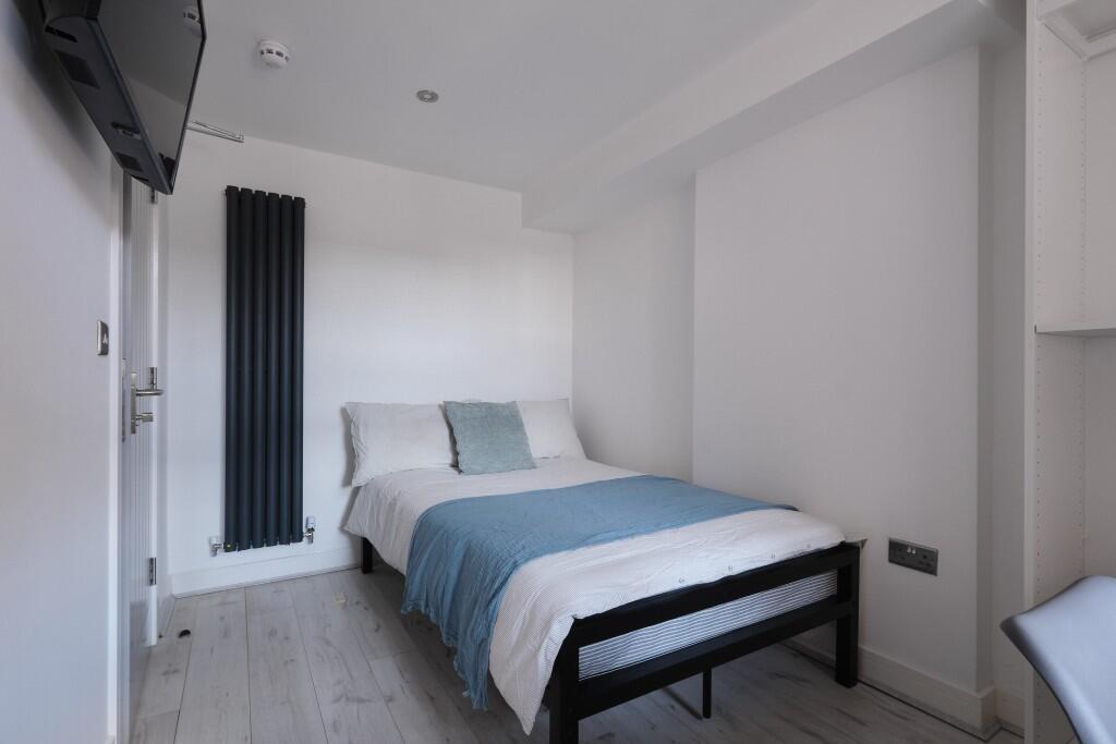 A bright, tidy bedroom featuring a comfortable ...
