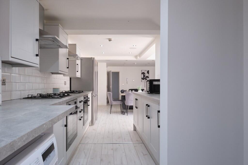 Bright modern kitchen with light cabinetry, til...