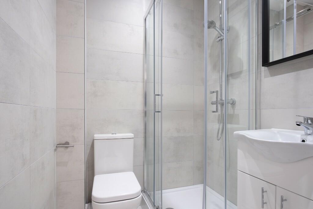 A modern bathroom featuring a toilet, shower ar...