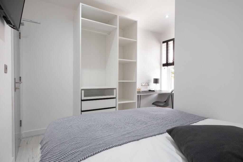 A bright and tidy bedroom with a double bed, mi...