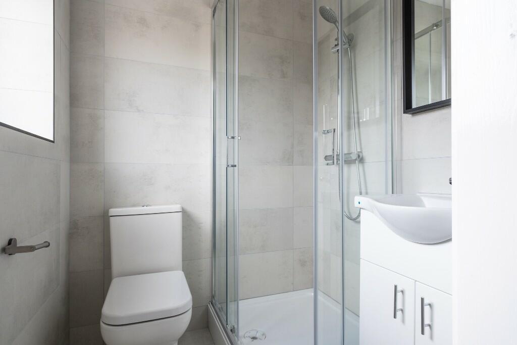 A modern bathroom featuring a toilet, a glass-e...