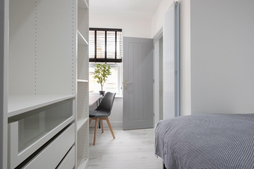 A bright, stylish bedroom with a comfortable be...