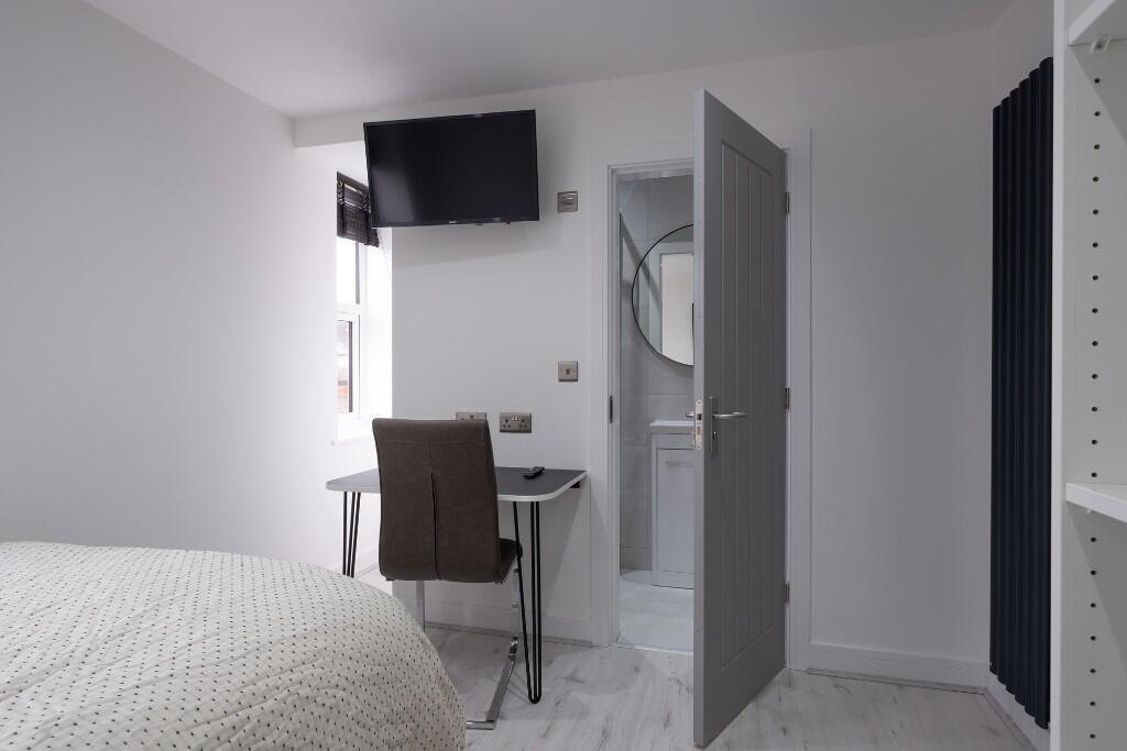 A tidy and well-lit bedroom featuring a bed and...