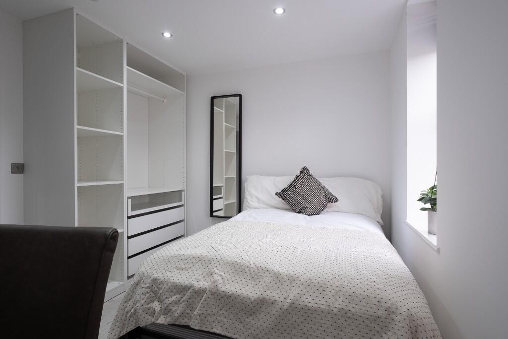 A bright and tidy bedroom featuring a neatly ma...