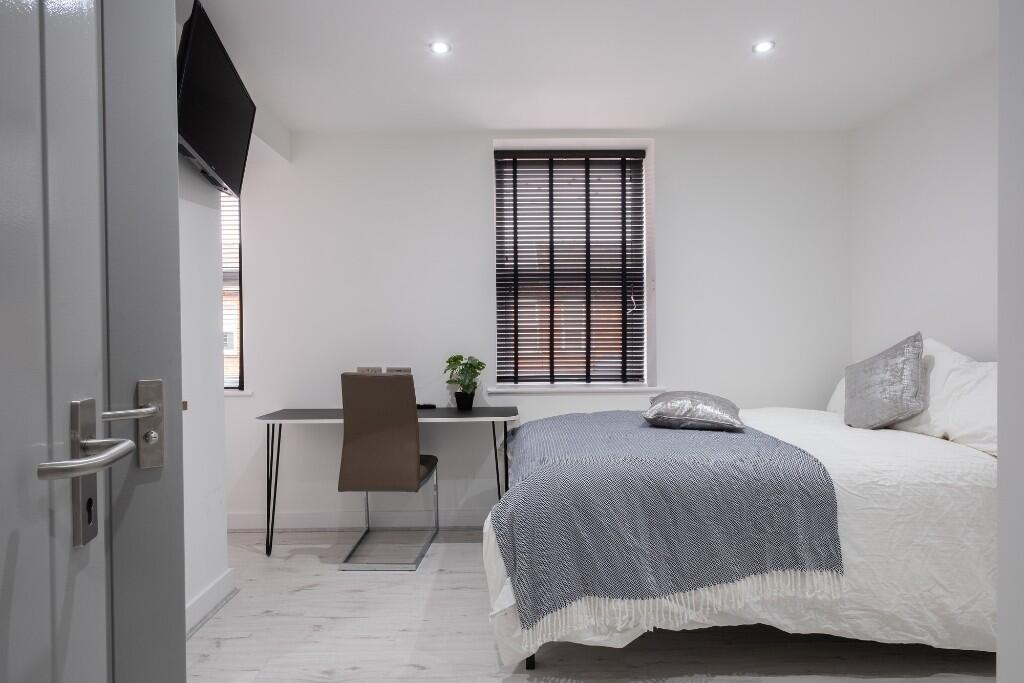 A bright and tidy bedroom featuring a comfortab...