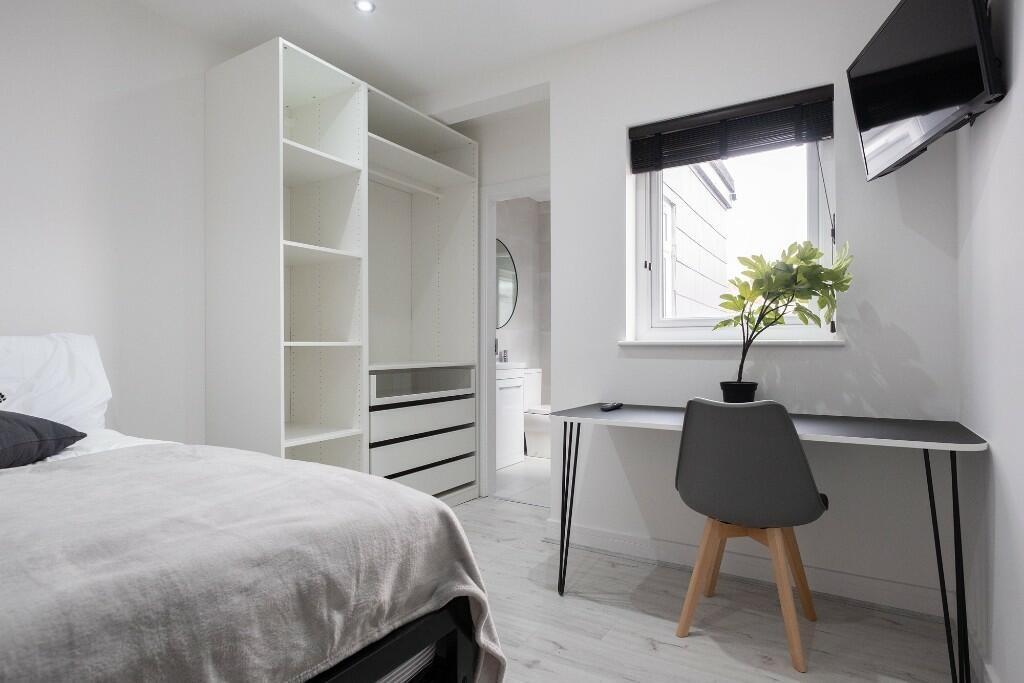 A modern and tidy bedroom featuring a large bed...