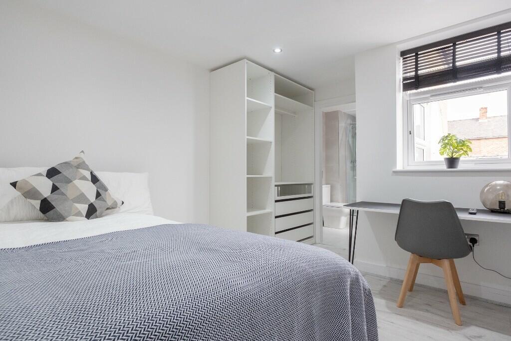 A bright and neatly arranged bedroom featuring ...