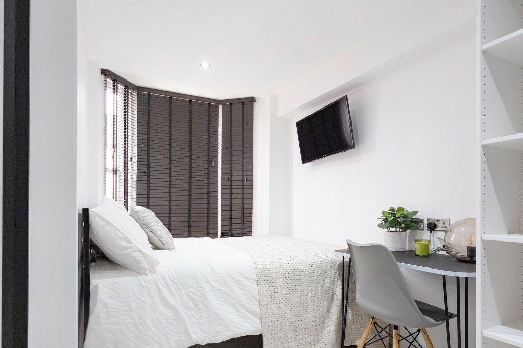 A bright, tidy bedroom featuring a comfortable ...