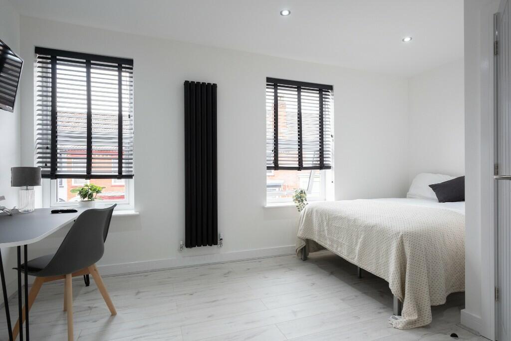 A bright and clean bedroom featuring two large ...