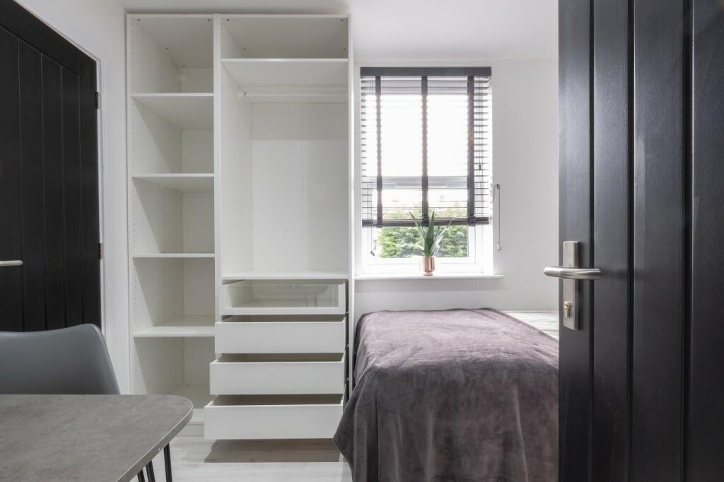 A well-lit bedroom featuring a bed with neatly ...