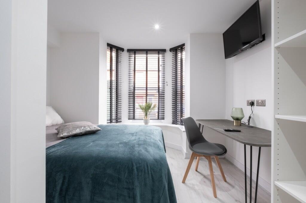 A modern bedroom with a stylish teal bedspread,...