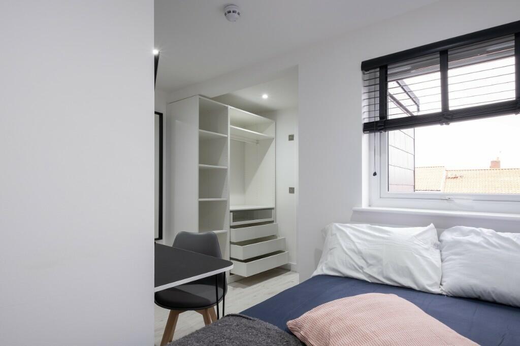 A bright and tidy bedroom featuring a comfortab...