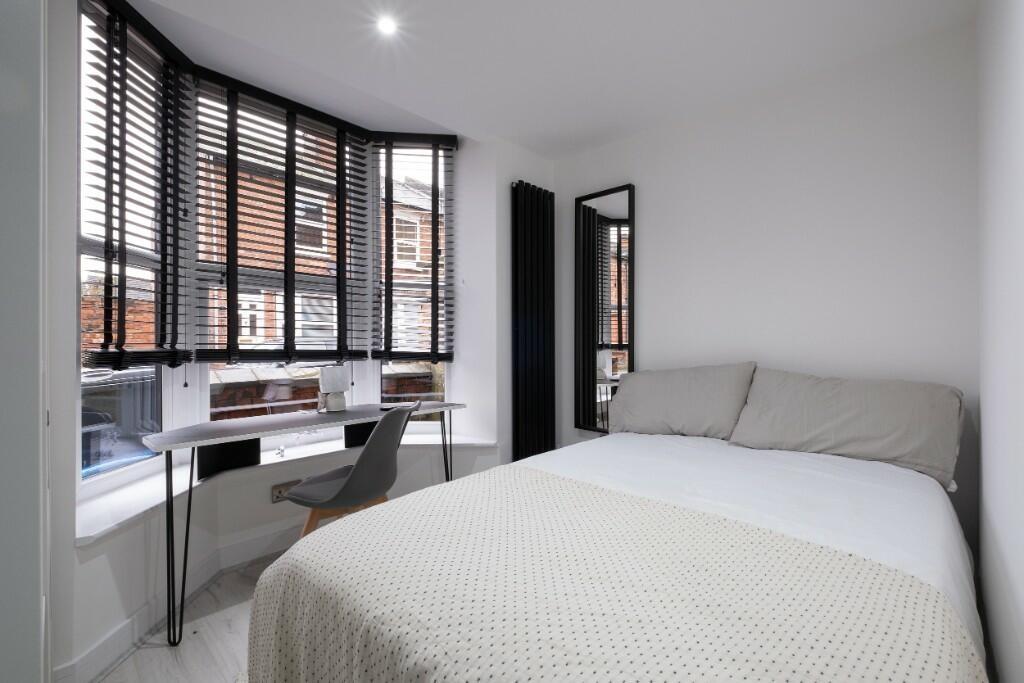 A bright and tidy bedroom featuring a large bed...