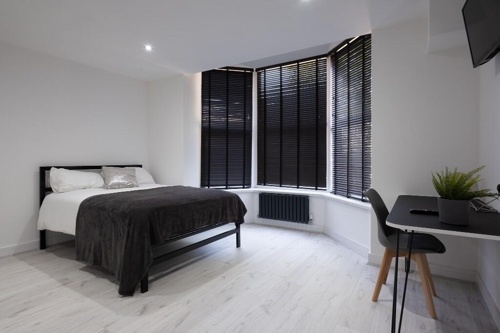 Bright and modern master bedroom featuring larg...