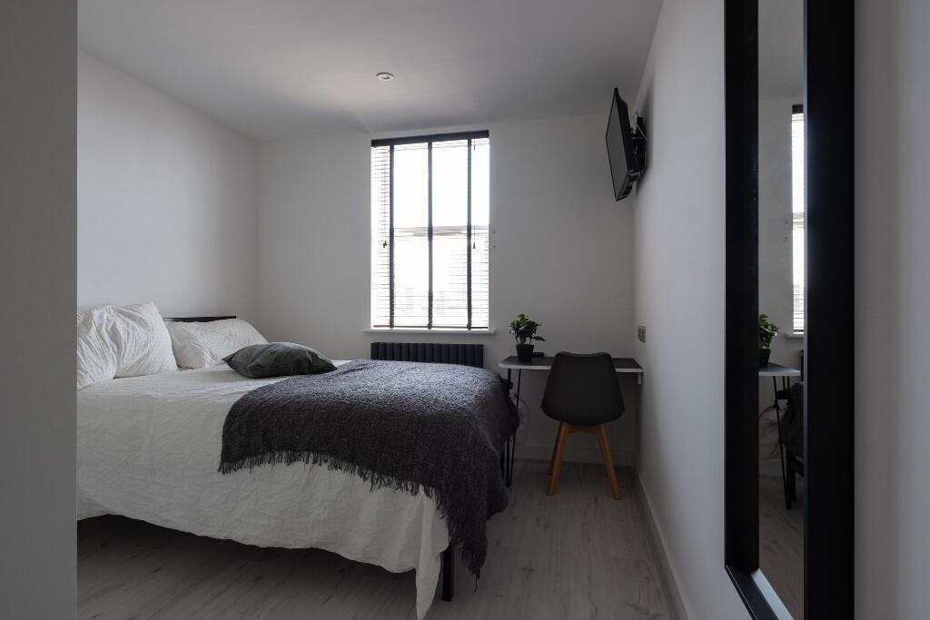 A spacious and tidy bedroom featuring a large b...