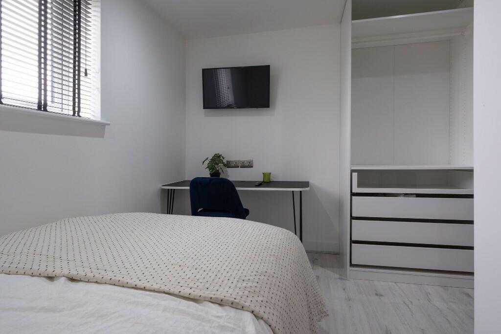 A bright, tidy bedroom featuring a comfortable ...