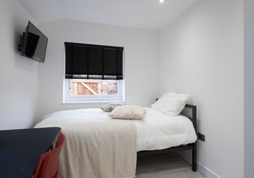 A bright and clean single bedroom with white wa...