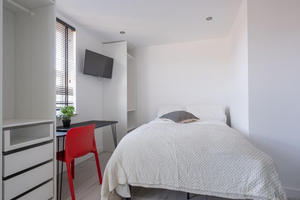 A bright, tidy single bedroom featuring a comfo...