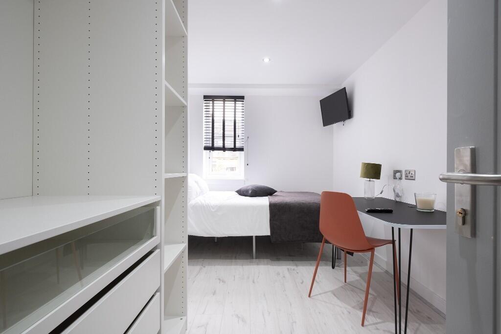 A bright and tidy student bedroom with a comfor...