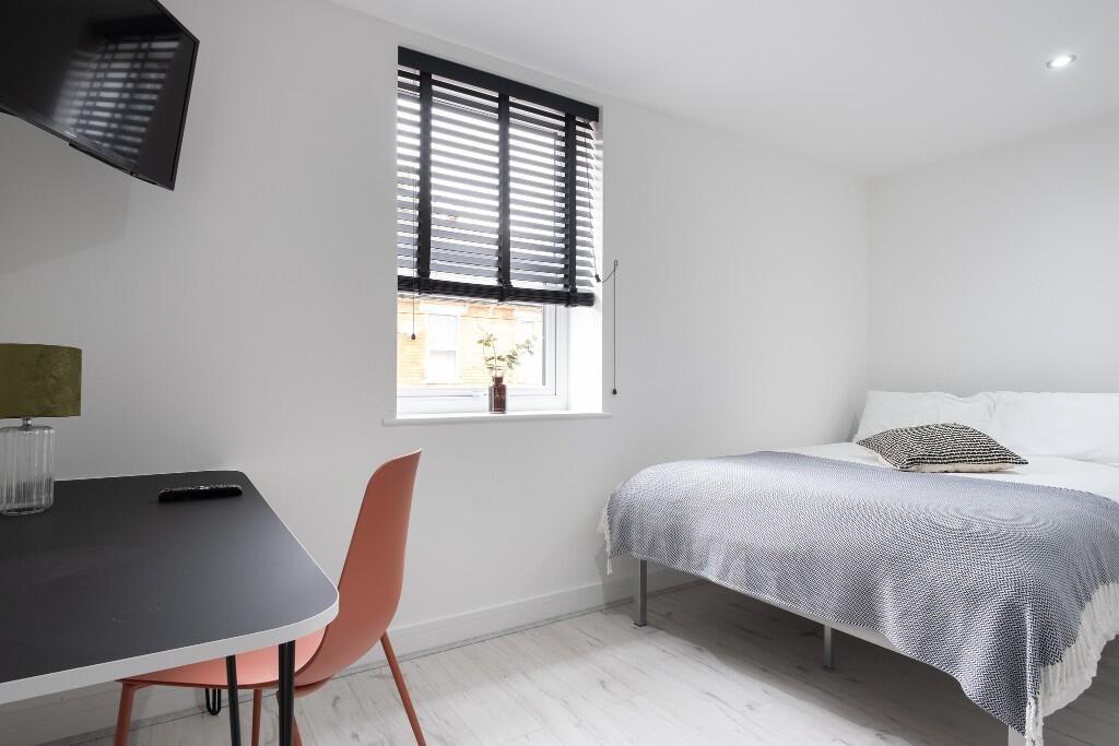 A clean and bright bedroom featuring a comforta...
