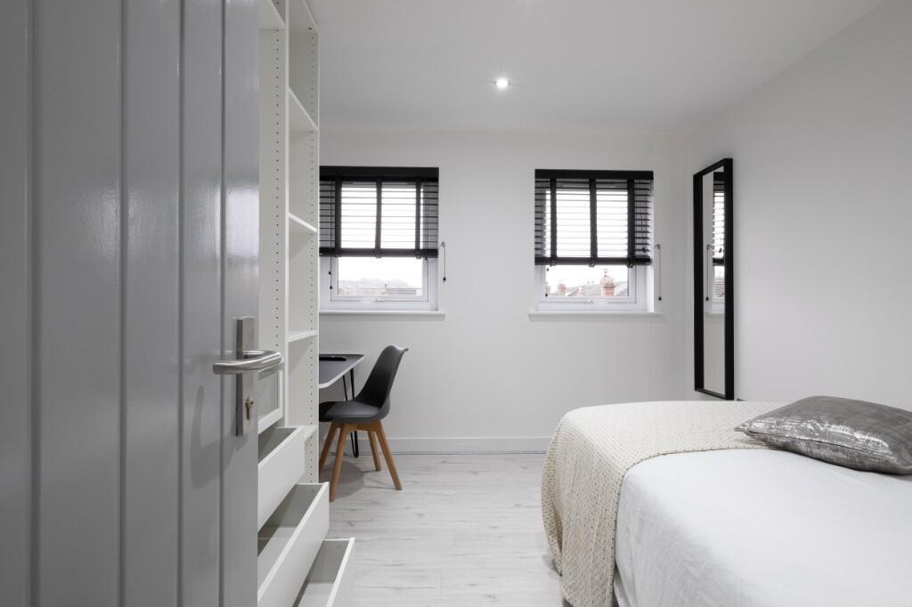 A bright and tidy bedroom featuring a comfortab...