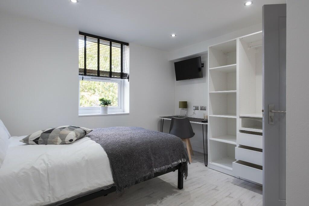 A bright and tidy bedroom featuring a comfortab...