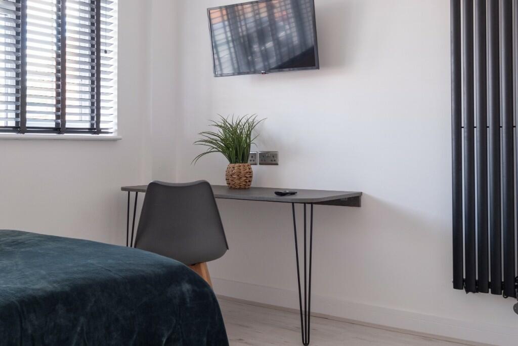 A modern bedroom featuring a bed, a workspace w...