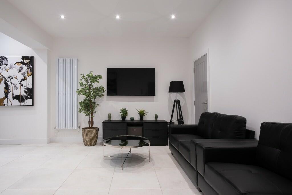 A modern, spacious living room with white walls...