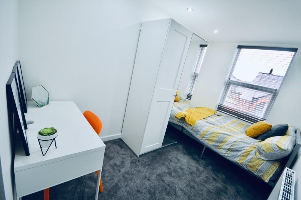 A bright and well-kept bedroom featuring a comf...