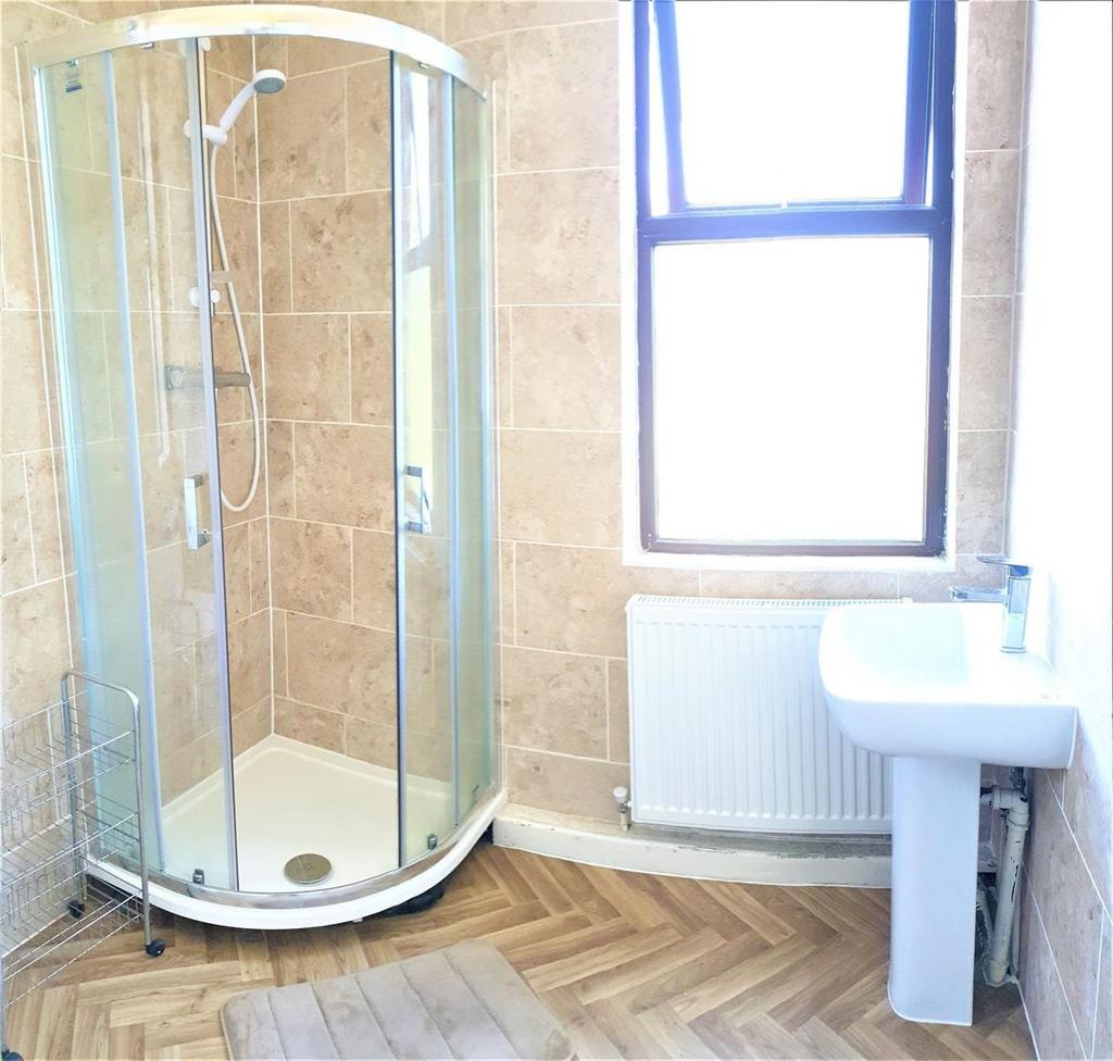Bright, tiled bathroom featuring a curved glass...