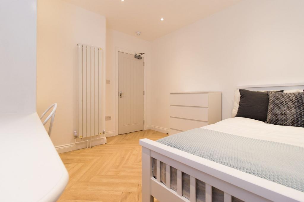 Bright, modern double bedroom with light wood f...
