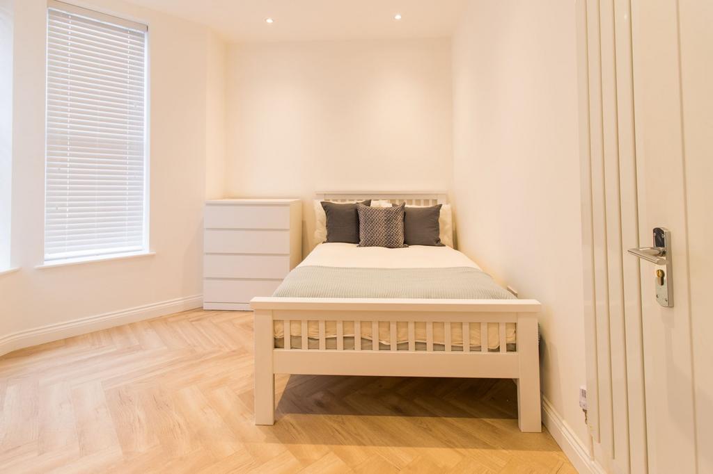 Bright, minimal bedroom with light wood chevron...