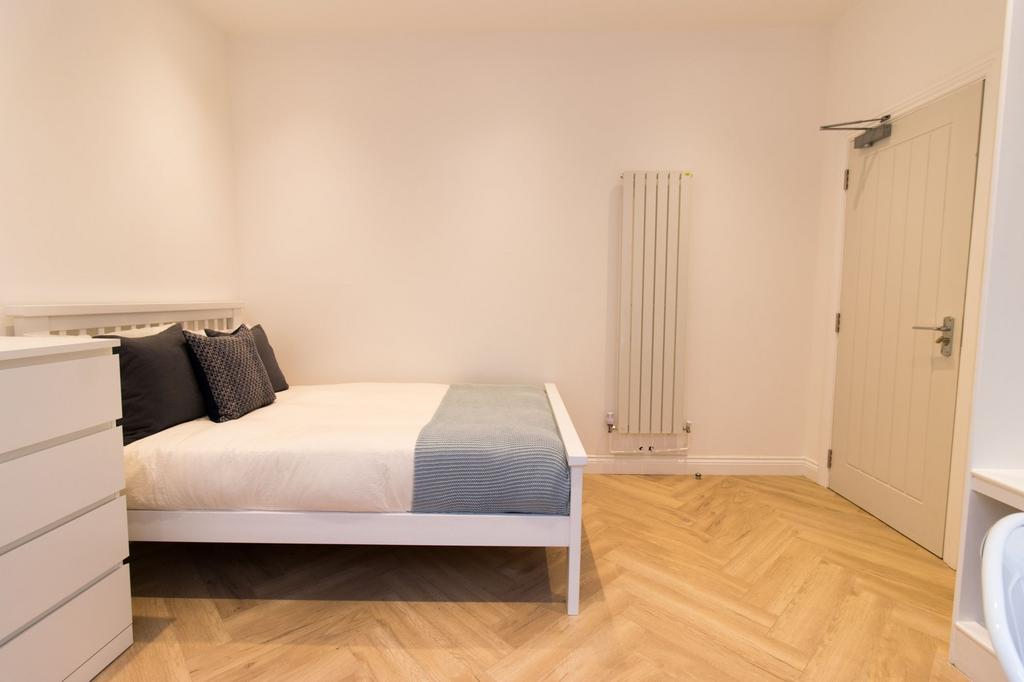 Bright, modern double bedroom with a white bedf...