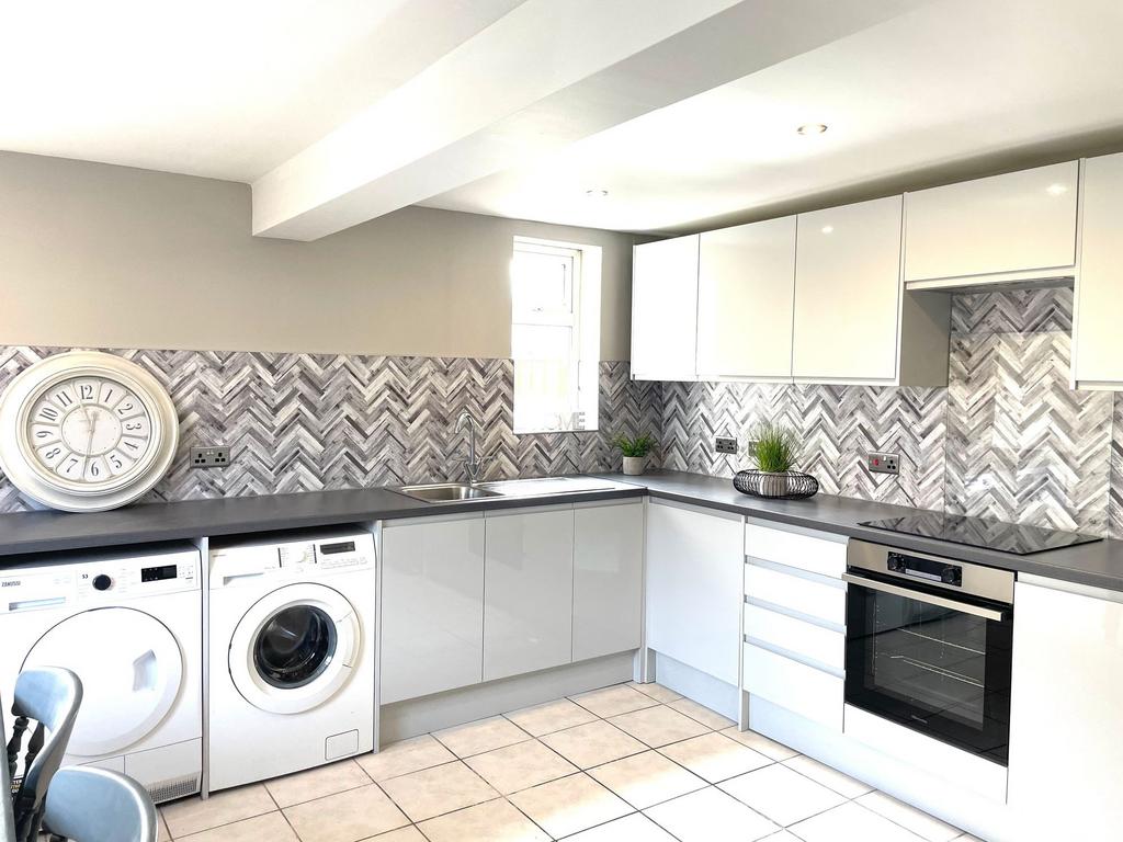 Modern kitchen with white cabinetry, stylish ba...