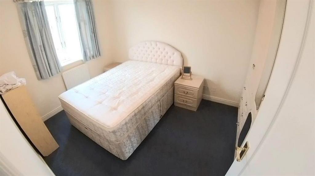 A small, clean room featuring a basic bed and a...
