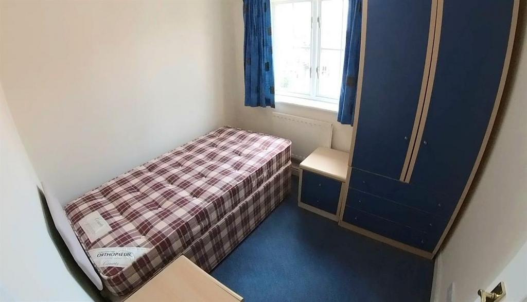 A cozy single bedroom featuring a small bed wit...