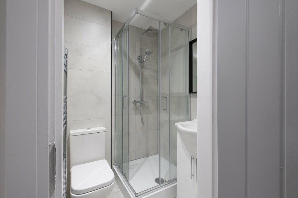 A modern, clean bathroom featuring a shower enc...