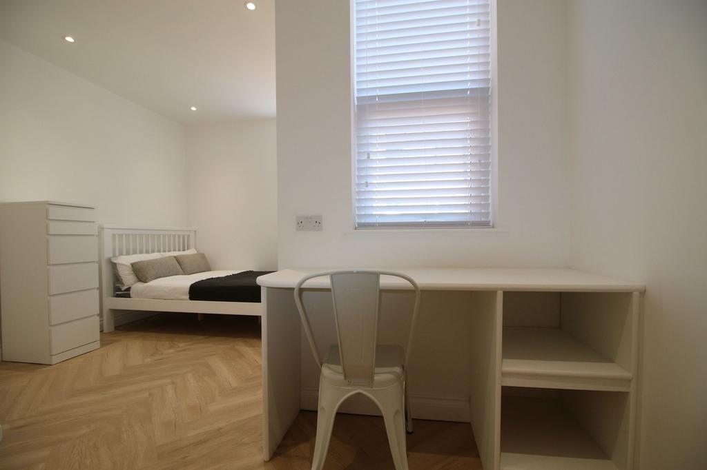 Bright, modern bedroom with pale wood herringbo...