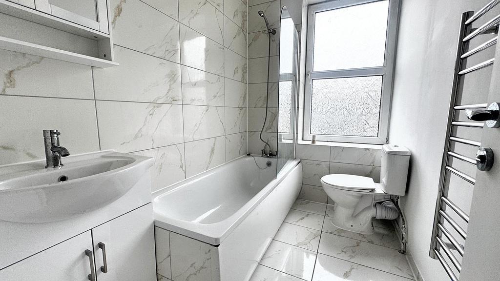 Bright, modern tiled bathroom with a full batht...