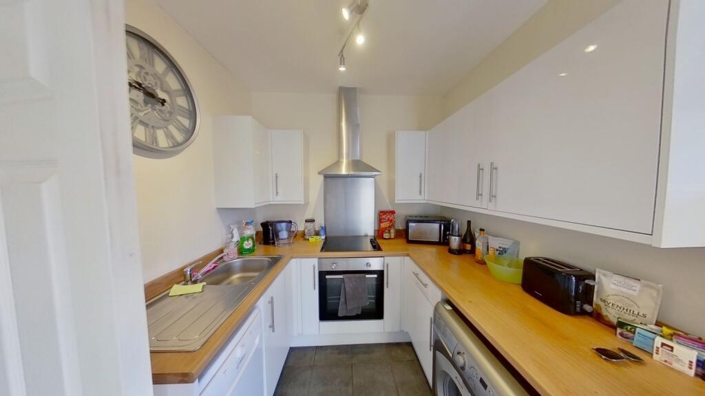 Bright modern galley kitchen with white cabinet...