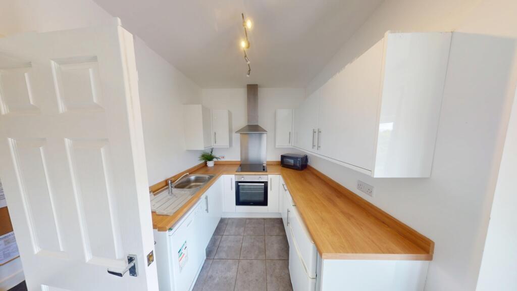 Bright modern galley kitchen with white cabinet...